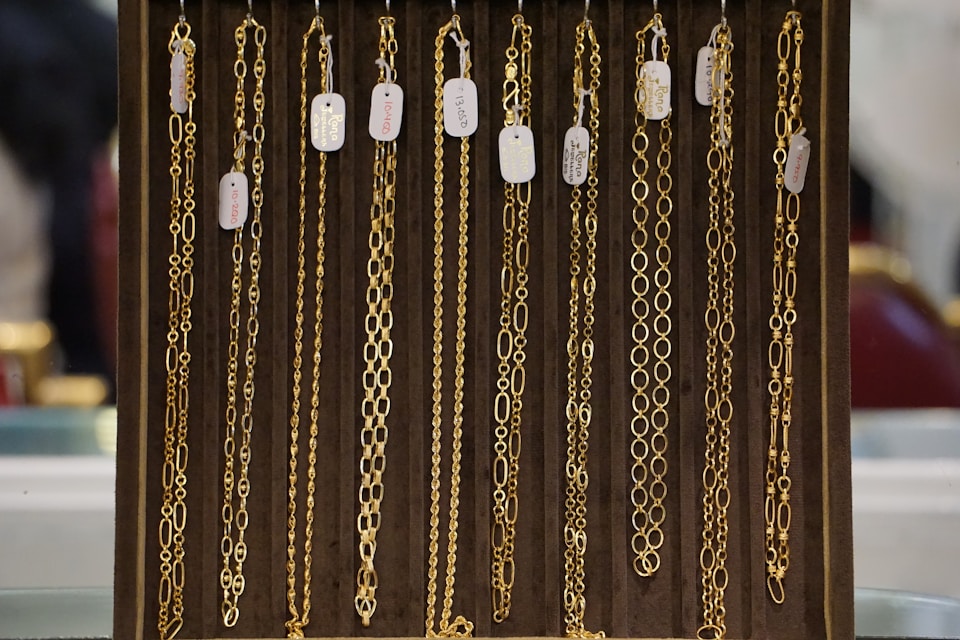 "Stack of gleaming gold necklaces in a display case."