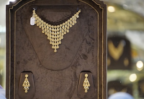 a gold necklace and earring set in a display case