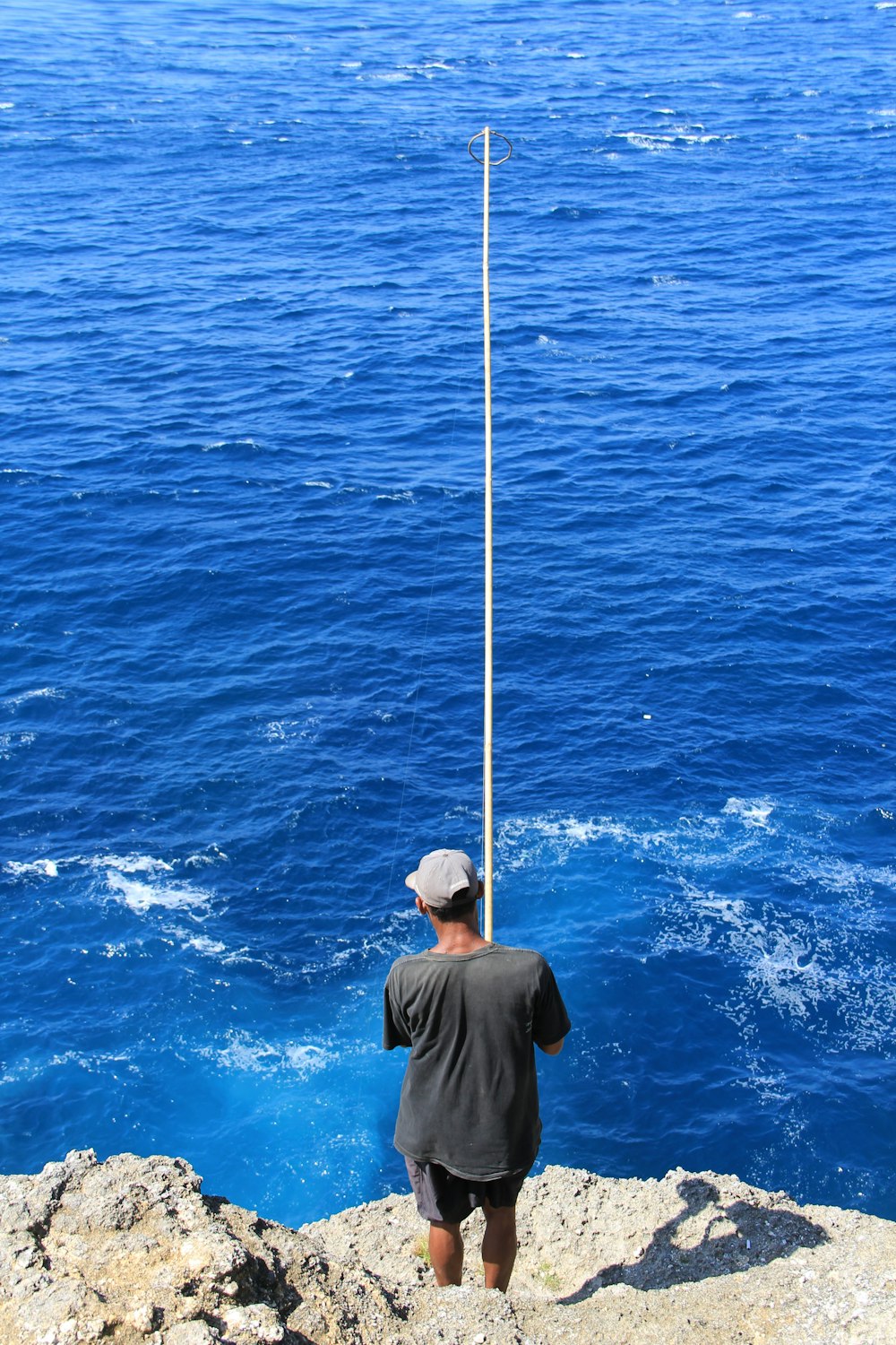 a man standing on top of a cliff next to the ocean