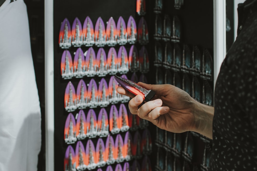 a person holding a cell phone in front of a rack of shoes