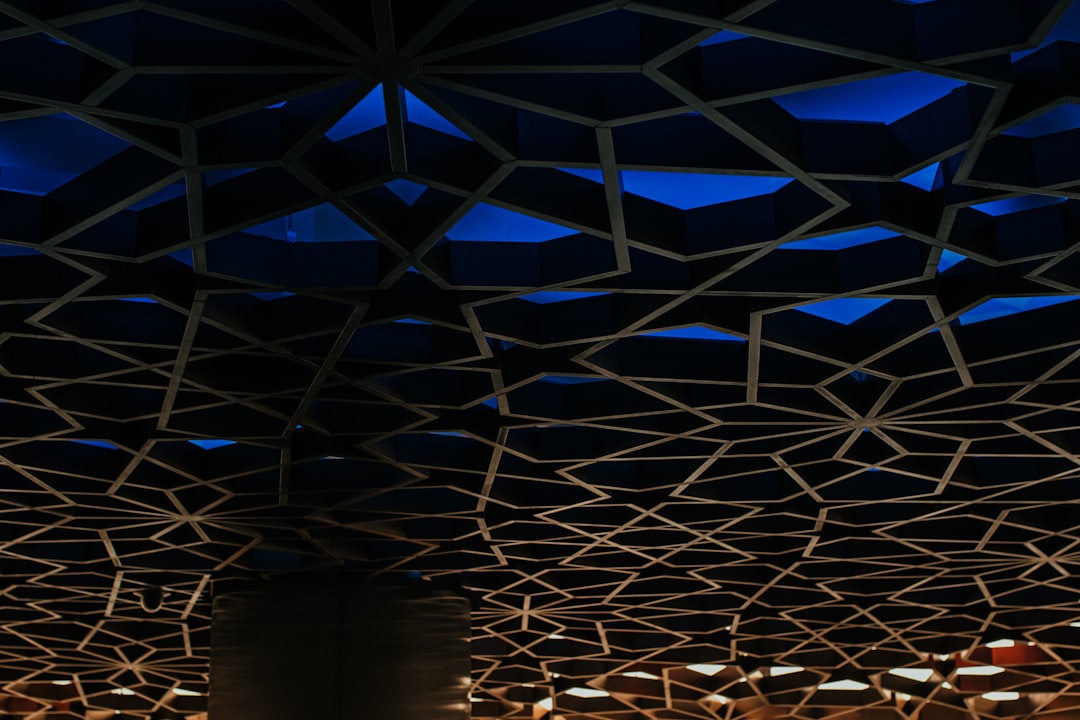 a room with a blue ceiling and a clock on the wall, Geometric arabic pattern design background with blue lighting interi
