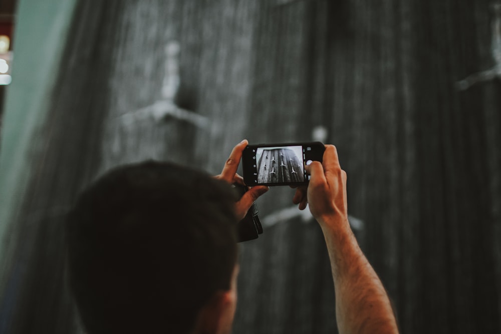 Ein Mann, der mit seinem Handy eine Dusche fotografiert