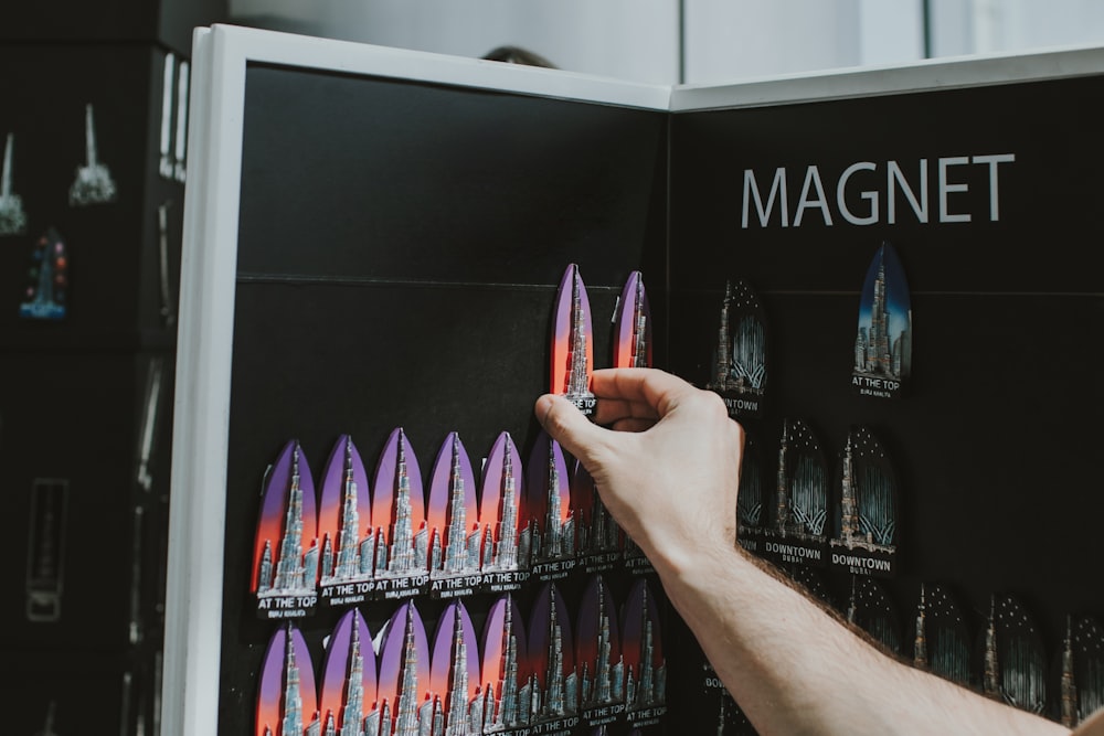 a person holding a book in front of a display of magnets