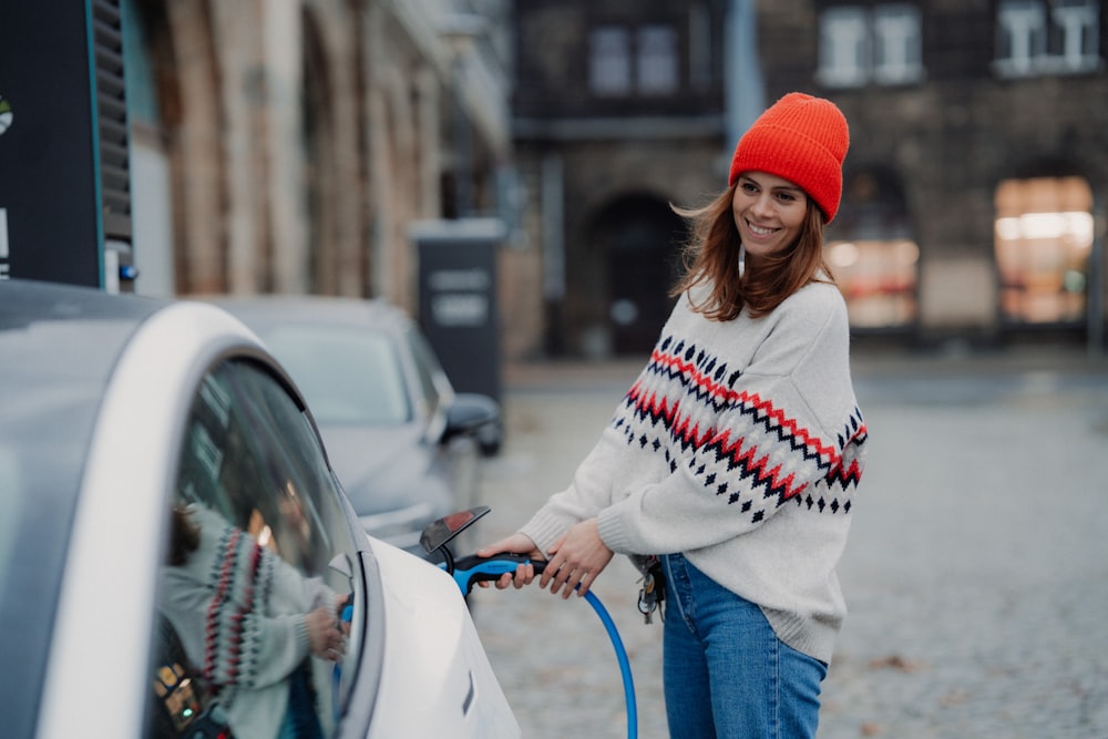 a woman in a red hat is pumping gas into a car