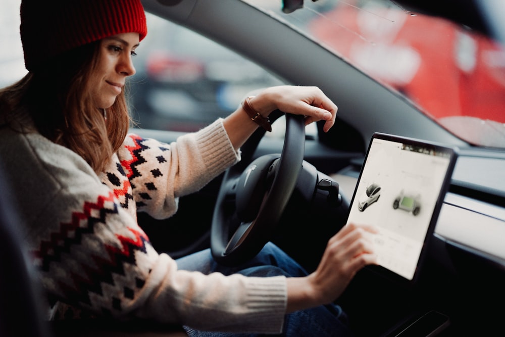 a woman sitting in a car holding a tablet