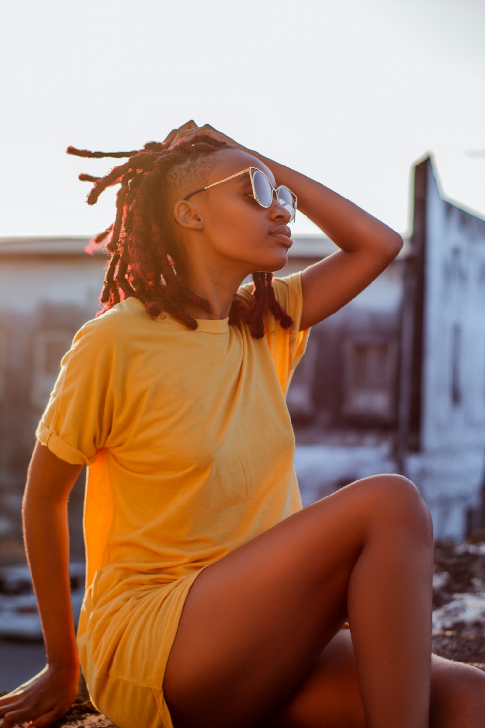 a woman with dreadlocks sitting on a rock