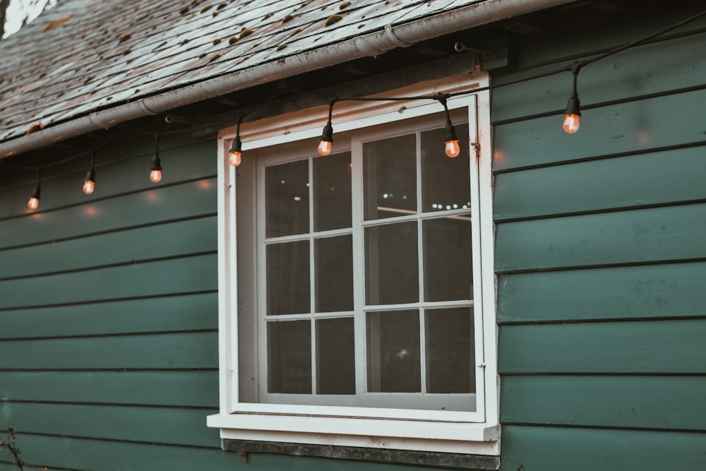 a green house with a window and string lights