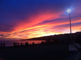 A vibrant sunset over Agadir beach with locals and tourists enjoying the view.