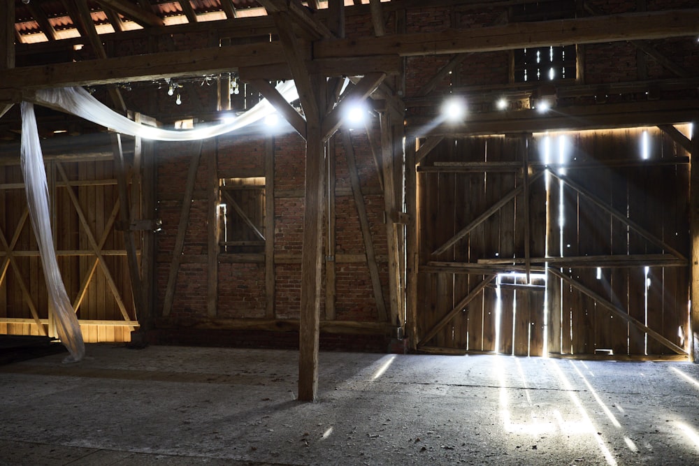an empty barn with beams of light shining through the windows