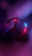 A metallic logo with a circular shape and three-pointed star inside is highlighted against a backdrop featuring gradients of deep blue, purple, and pink. The star and circle are illuminated with neon hues, creating a futuristic and sleek appearance. A starry sky adds depth to the background.