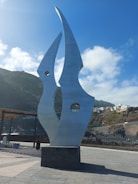 A vibrant metal sculpture glinting under the alpine sun with mountain peaks in the background