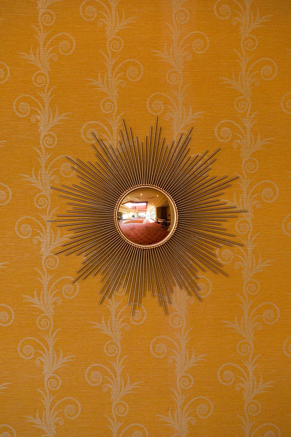 a sunburst shaped mirror on a yellow wall