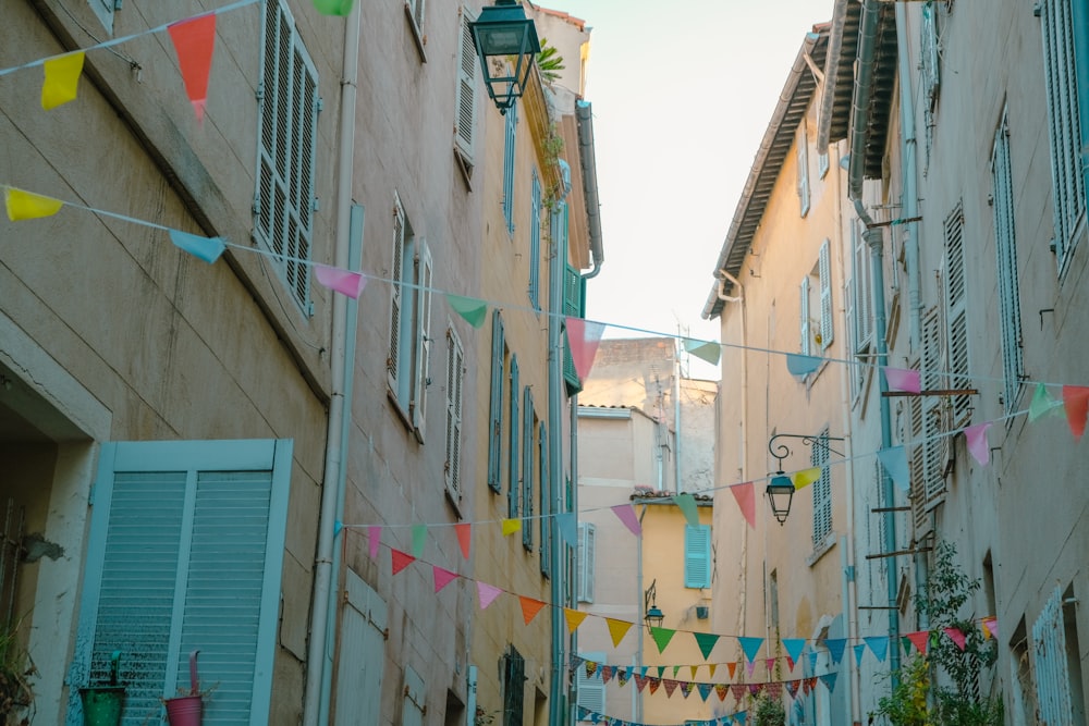 a narrow city street with colorful flags hanging from buildings