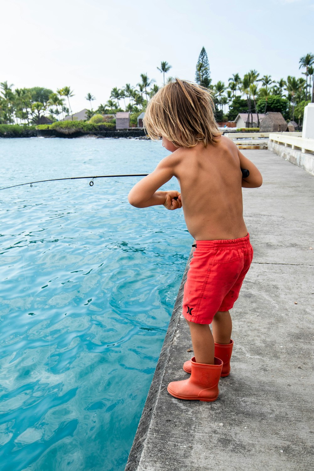 a young boy fishing in a pool of water