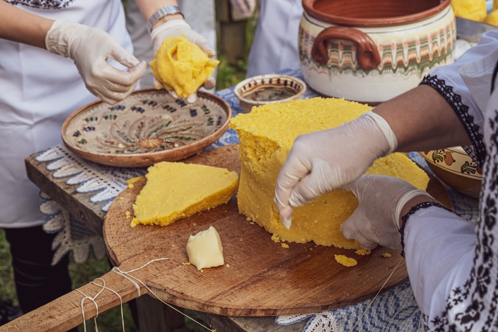 a person in white gloves cutting a piece of cake