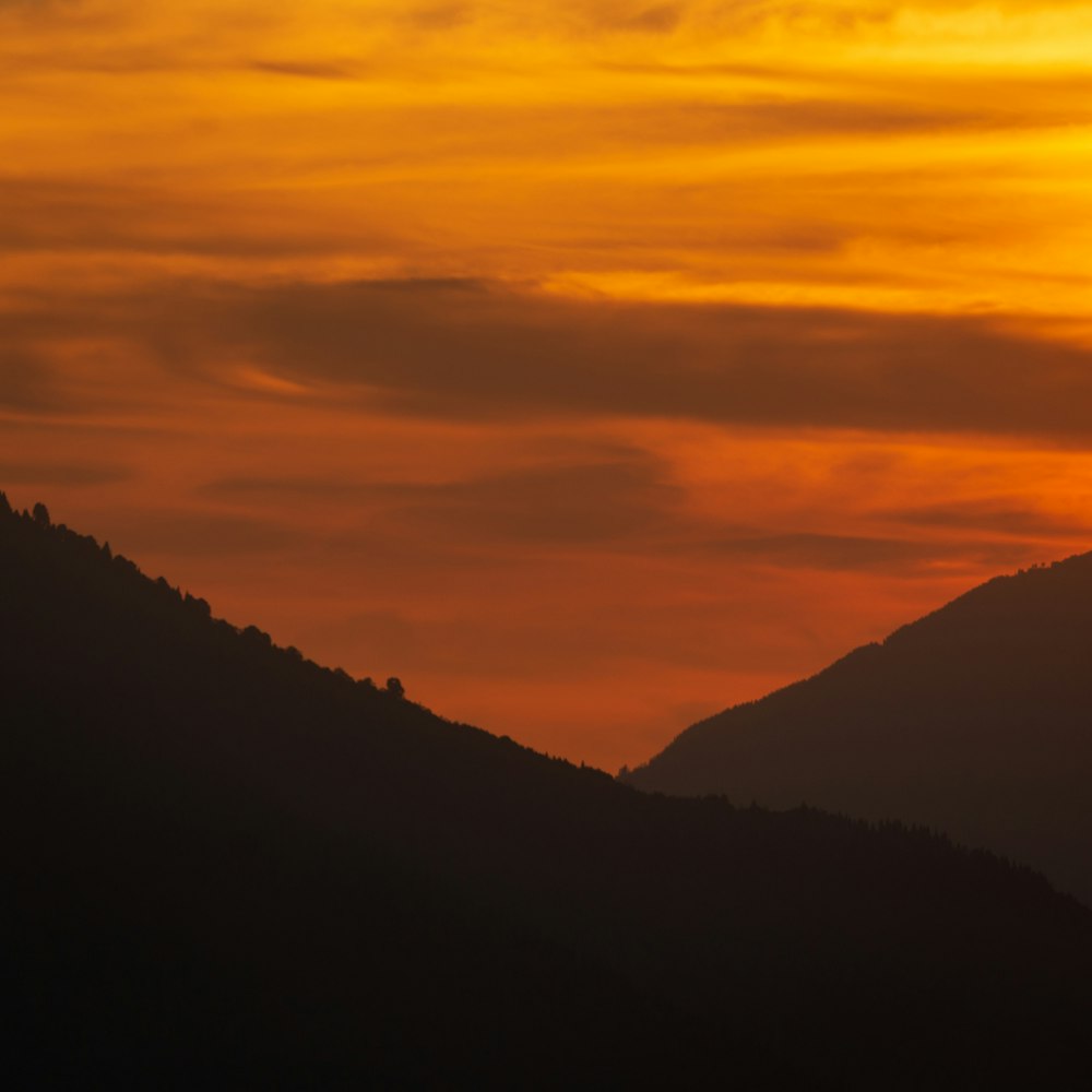 the sun is setting over a mountain range