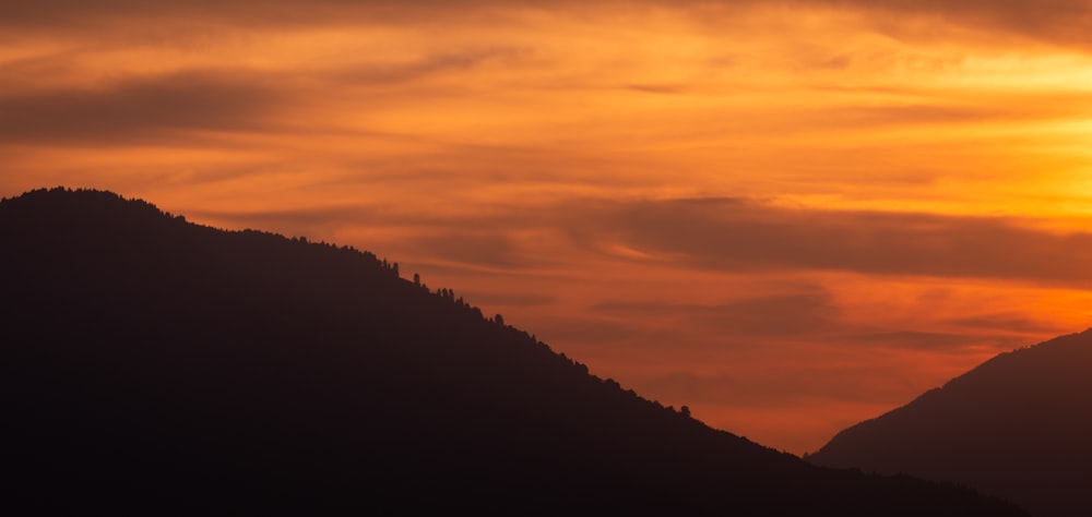 the sun is setting over a mountain range