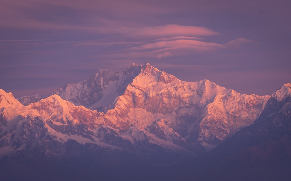 a snow covered mountain range under a purple sky