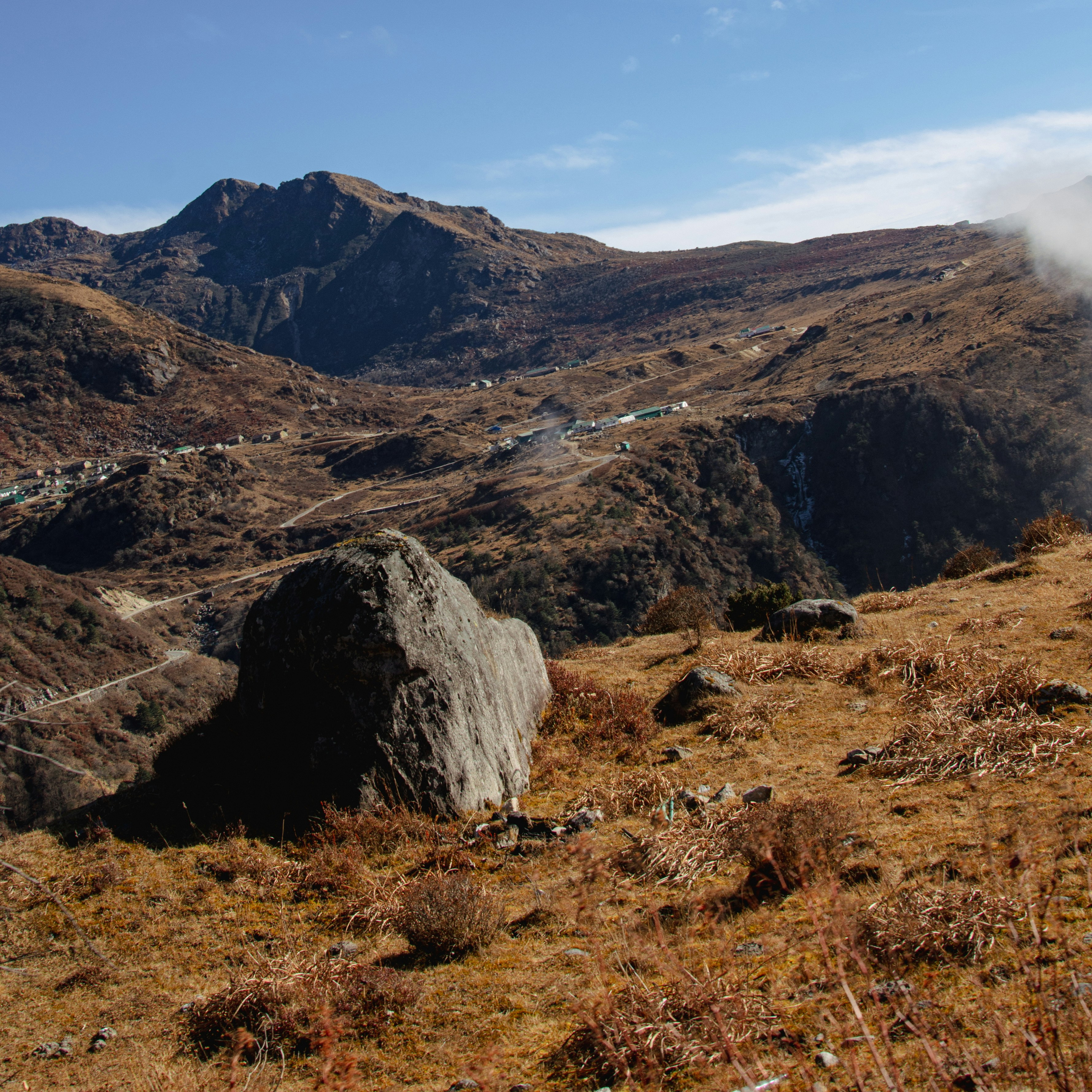 A large rock sitting on top of a grass covered hillside photo – Free ...