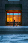 a person walking down a street with a snow shovel