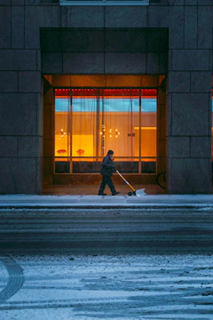 a person walking down a street with a snow shovel