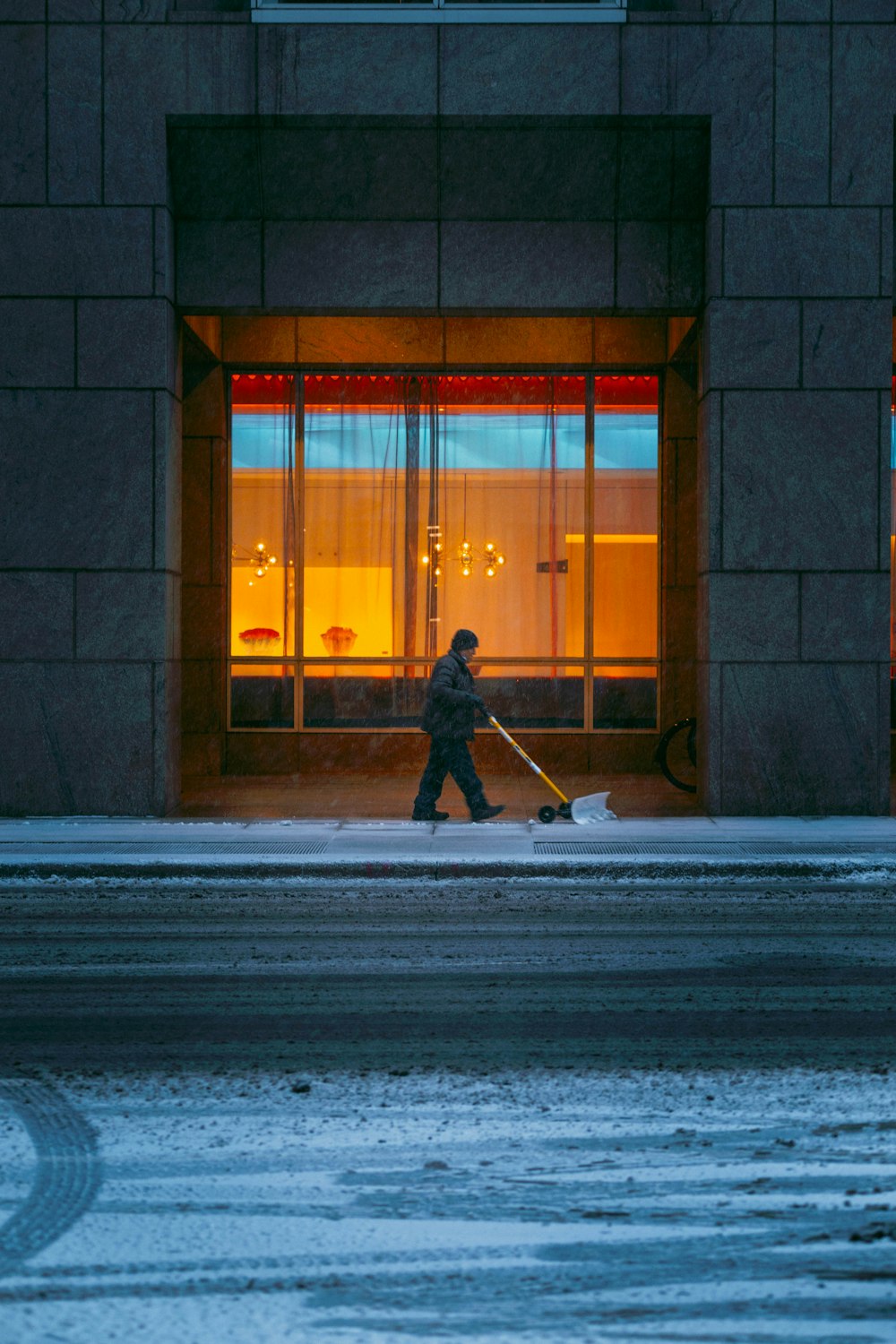 a person walking down a street with a snow shovel