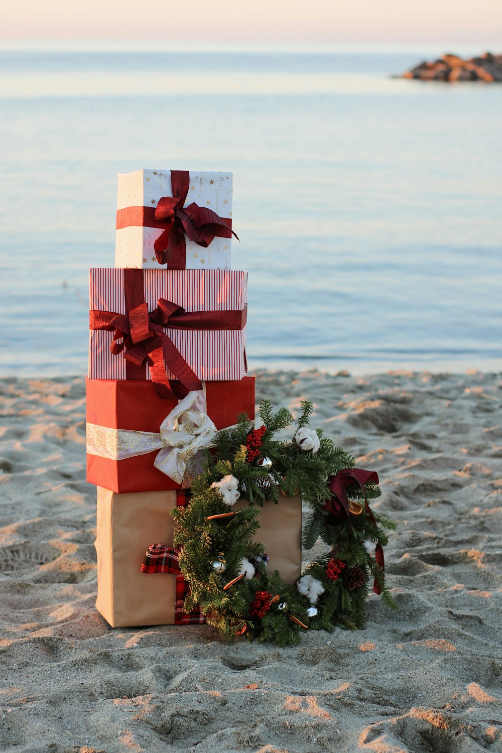 a stack of wrapped presents sitting on top of a sandy beach