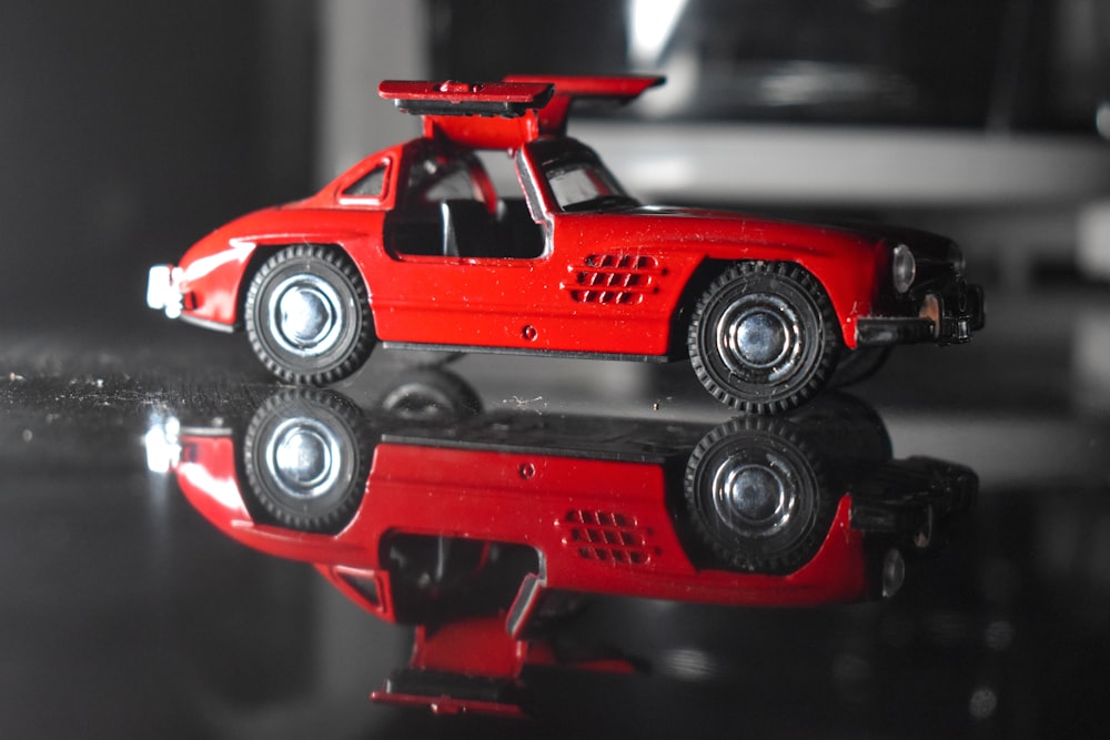 a red toy car sitting on top of a table
