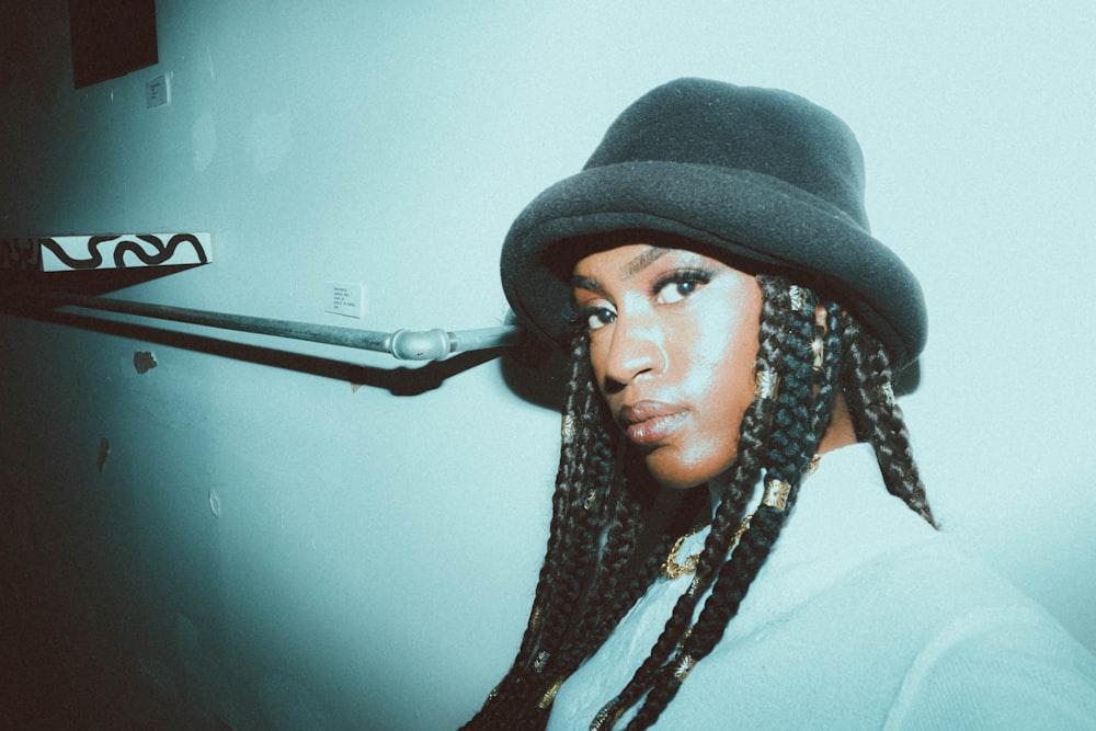 a woman wearing a hat and dreadlocks in a bathroom