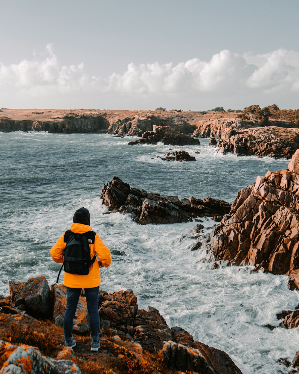 a person standing on rocks near the ocean