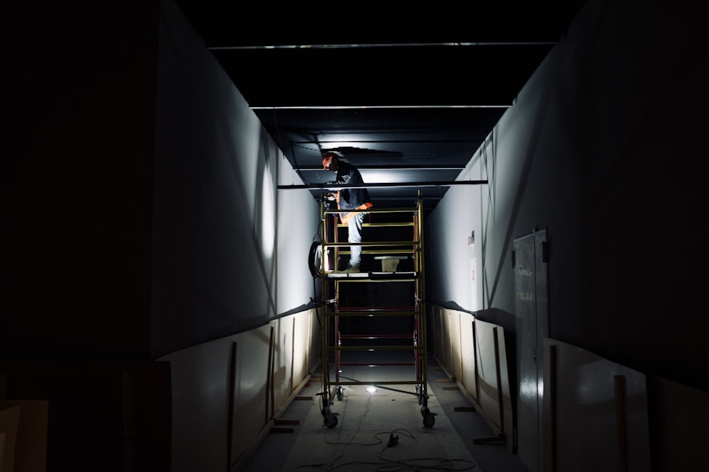 a man standing on a ladder in a dark room
