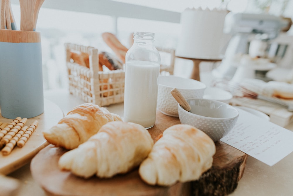 a table topped with croissants and a bottle of milk