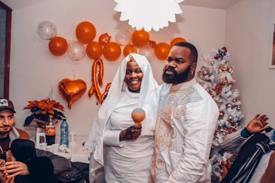 A happy couple smiling together, surrounded by their supportive families in a cozy home setting.