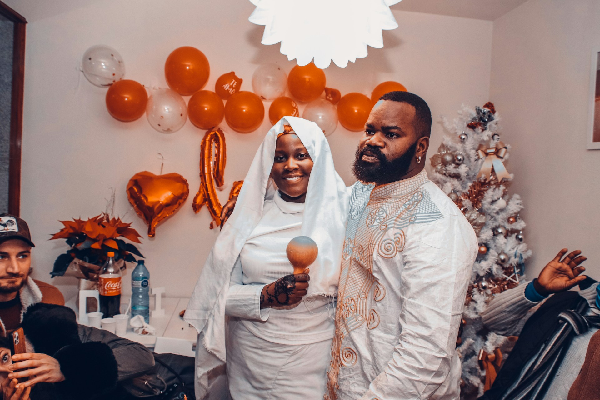 Close-up of a smiling couple holding instant photo strips from a bestlo photo booth, surrounded by festive decorations.