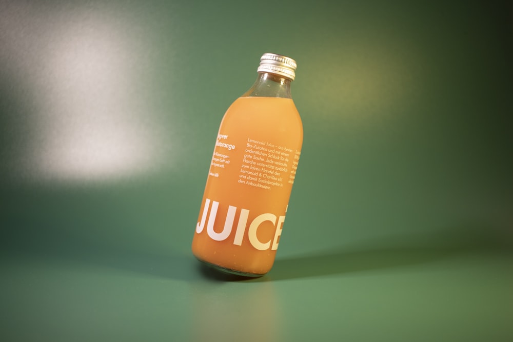 a bottle of juice sitting on a green surface