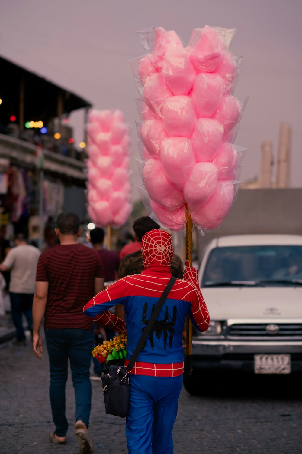 a person walking down a street holding a bunch of pink balloons