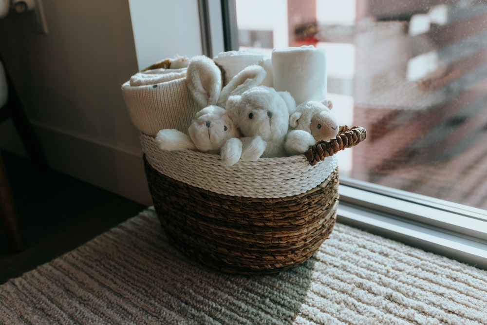 a basket filled with stuffed animals next to a window