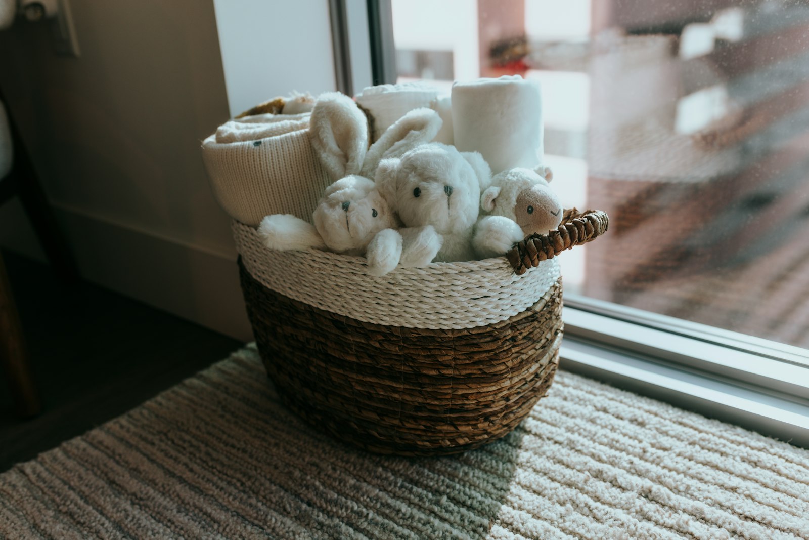 A wicker basket of stuffed animals beside a sunlit window