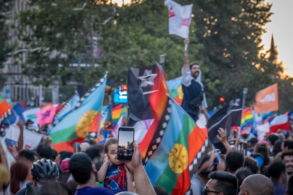 une grande foule de personnes tenant des drapeaux et des téléphones portables