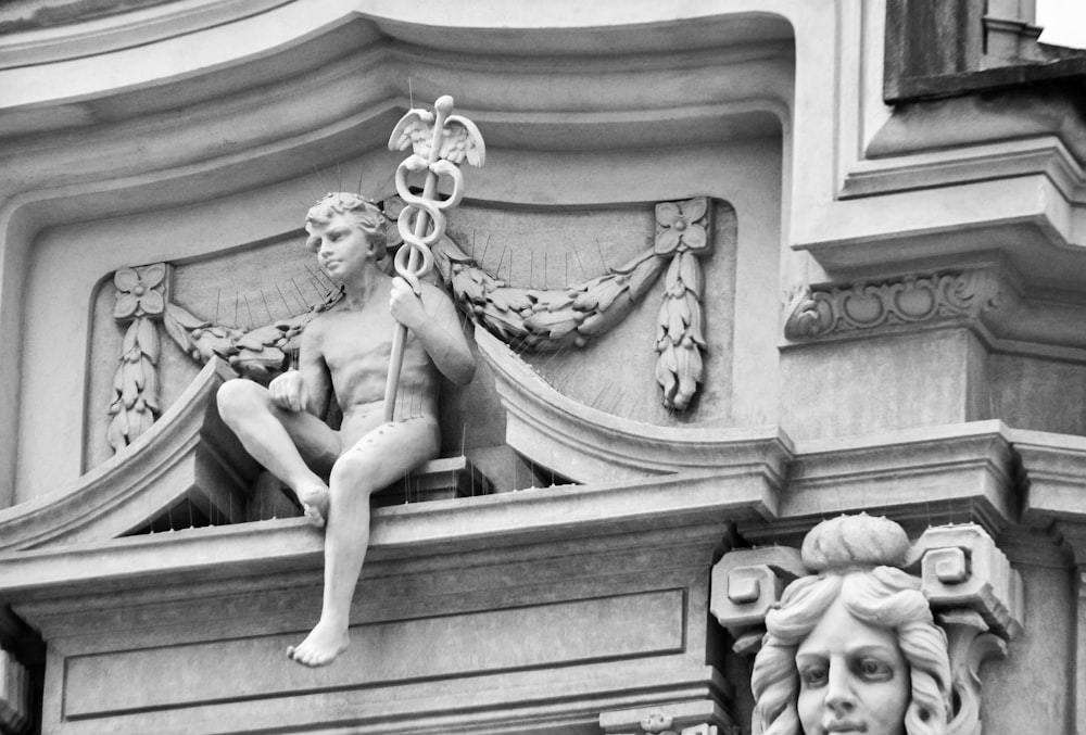 Una statua di un uomo seduto sulla cima di un edificio