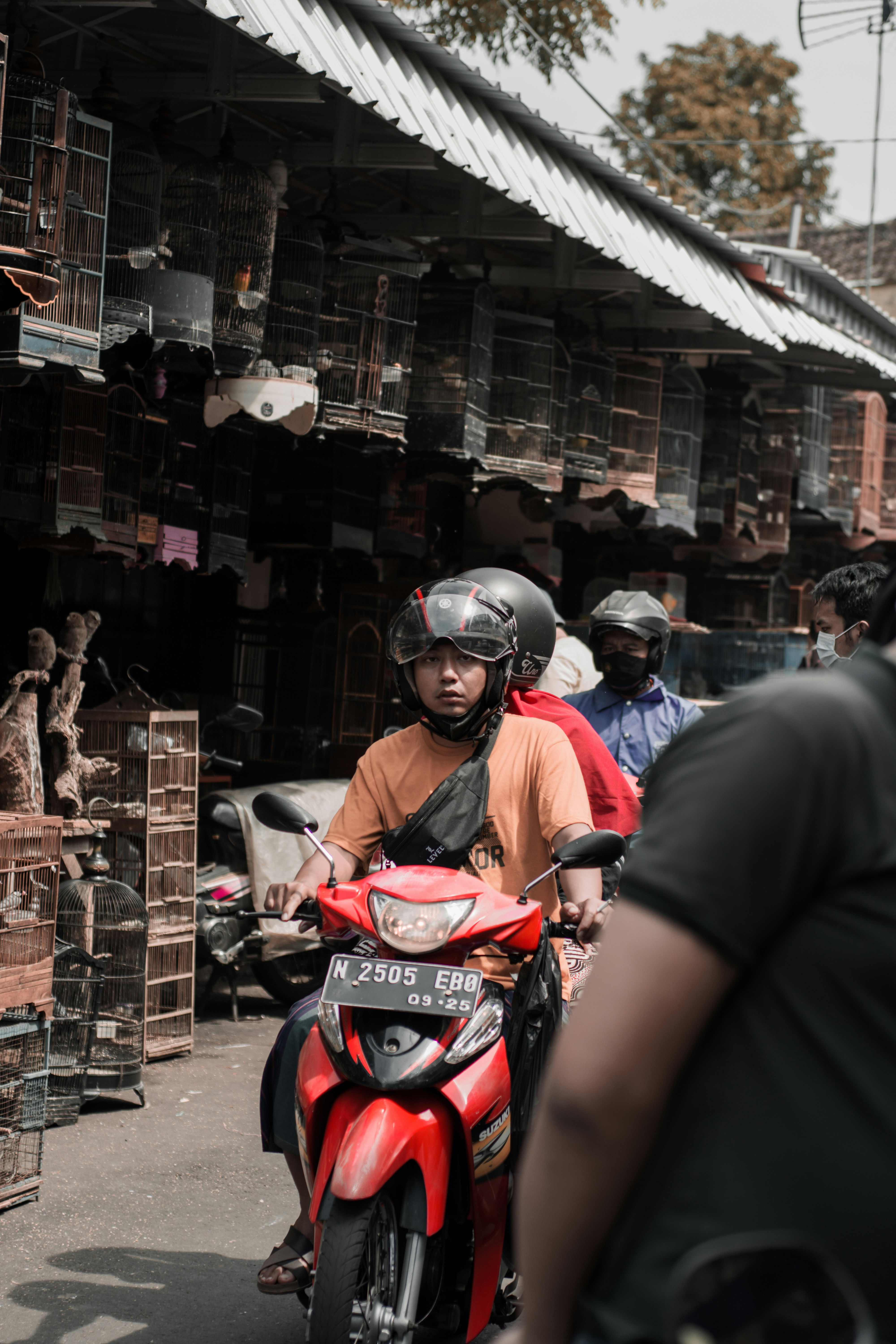 Seorang pria mengendarai sepeda motor merah di jalan