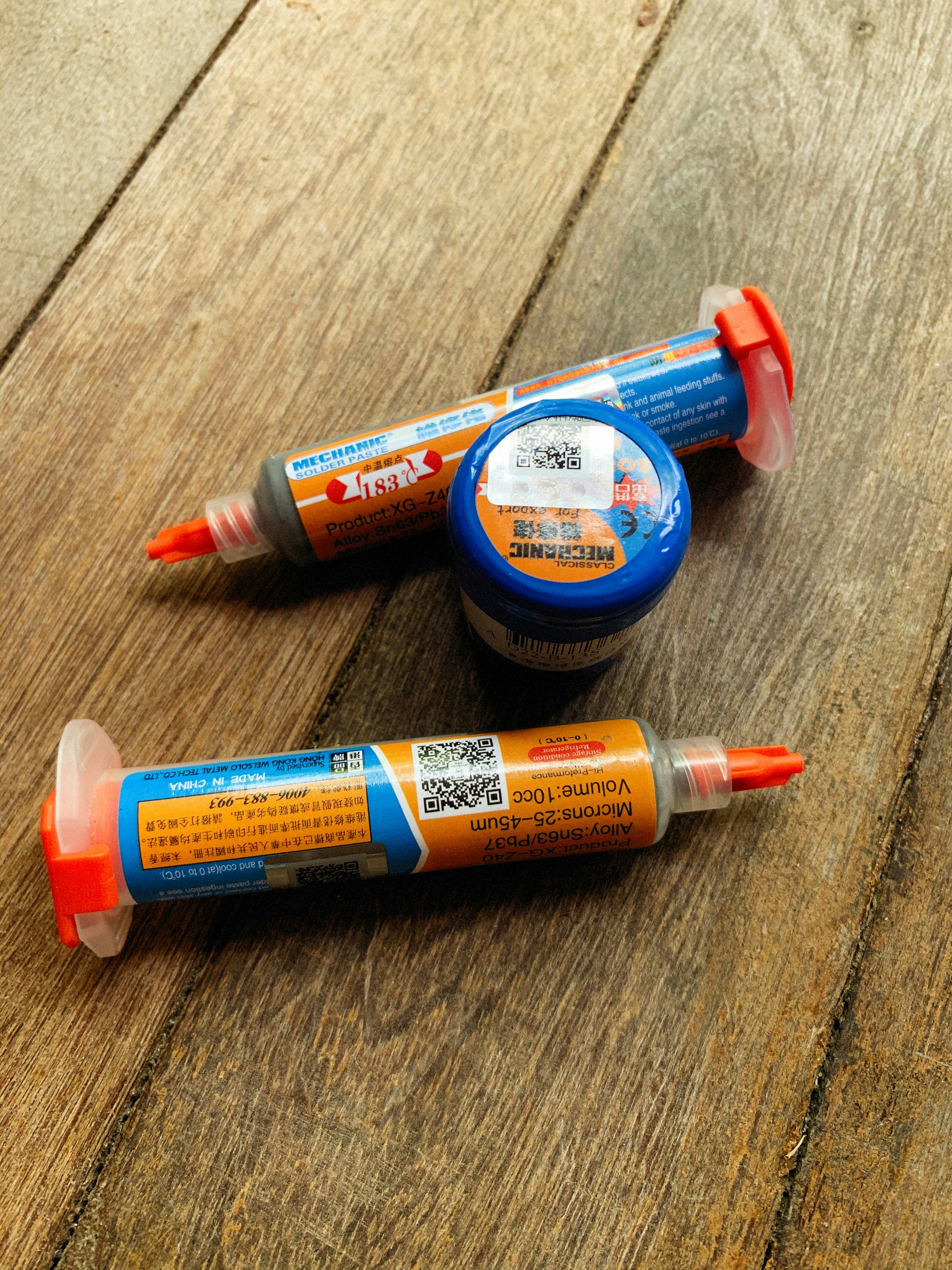 Tres marcadores naranjas y azules sentados encima de una mesa de madera