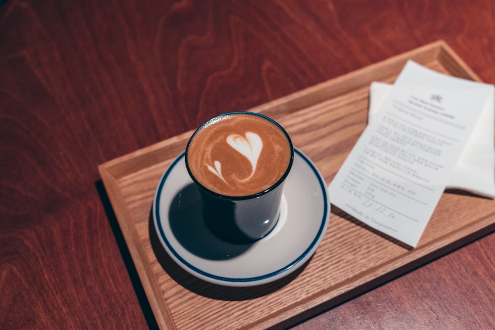 a cappuccino with a heart on it on a wooden tray