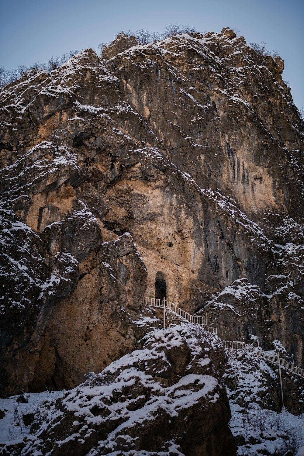 a mountain side with a fence and snow on the ground