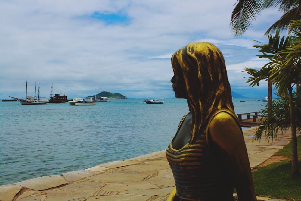 a statue of a woman standing next to a body of water