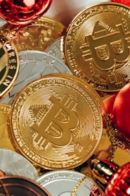 a pile of gold bitcoins next to a glass of wine
