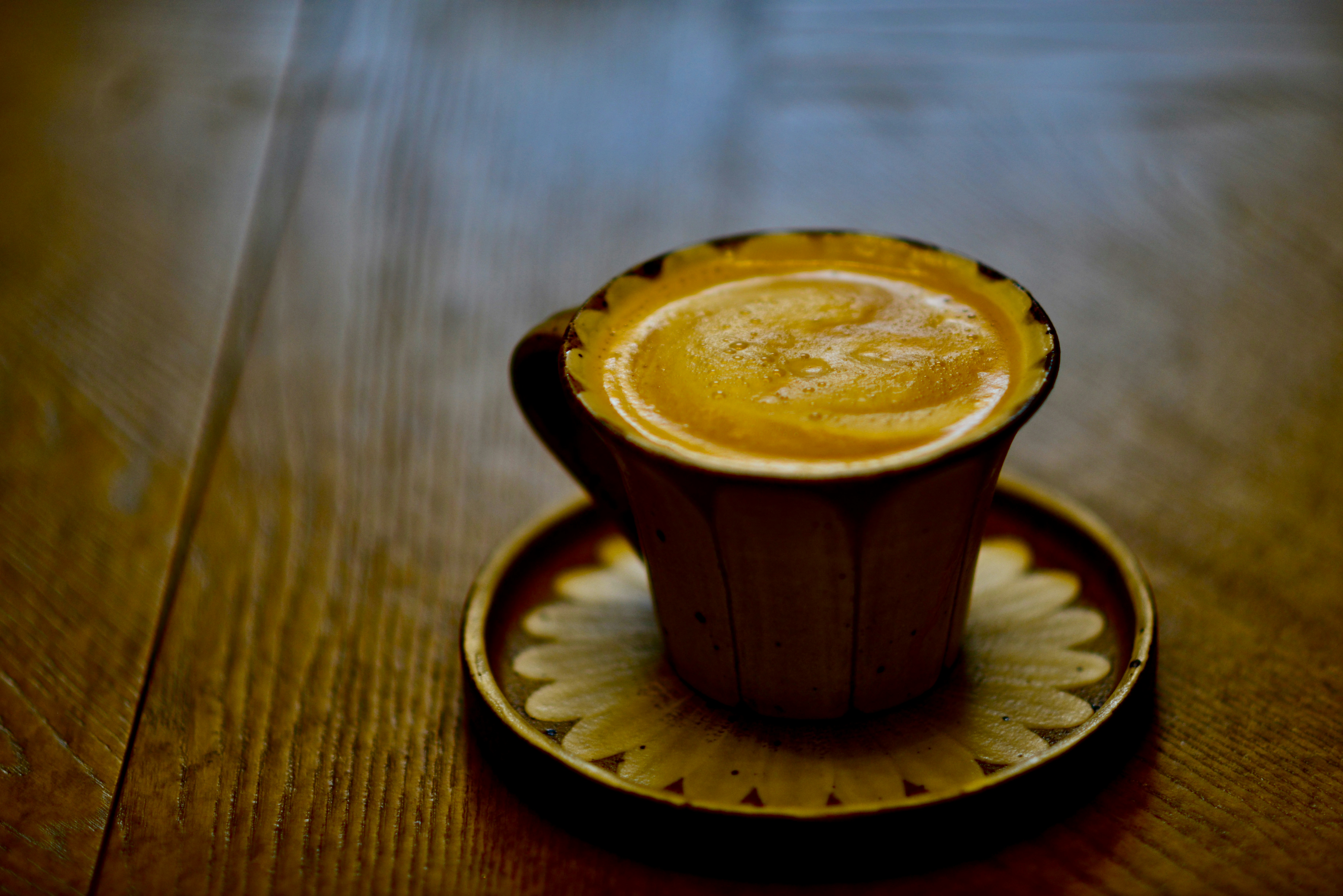 a cup of coffee sitting on top of a wooden table
