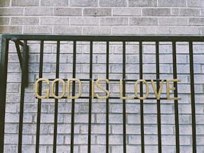 a sign that says god is love on a fence