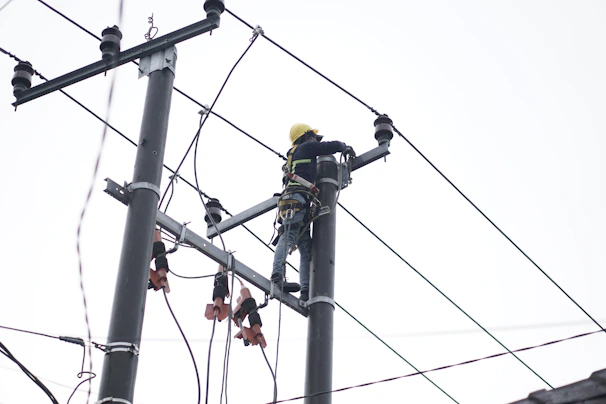 Electrician working carefully on residential wiring with tools and safety gear.