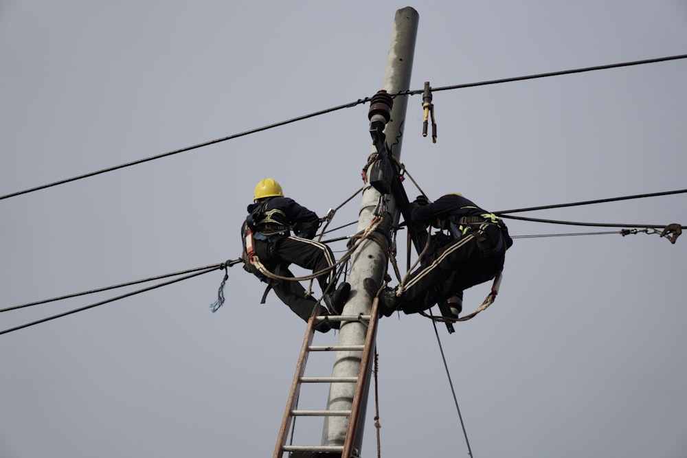 a man on a ladder working on power lines